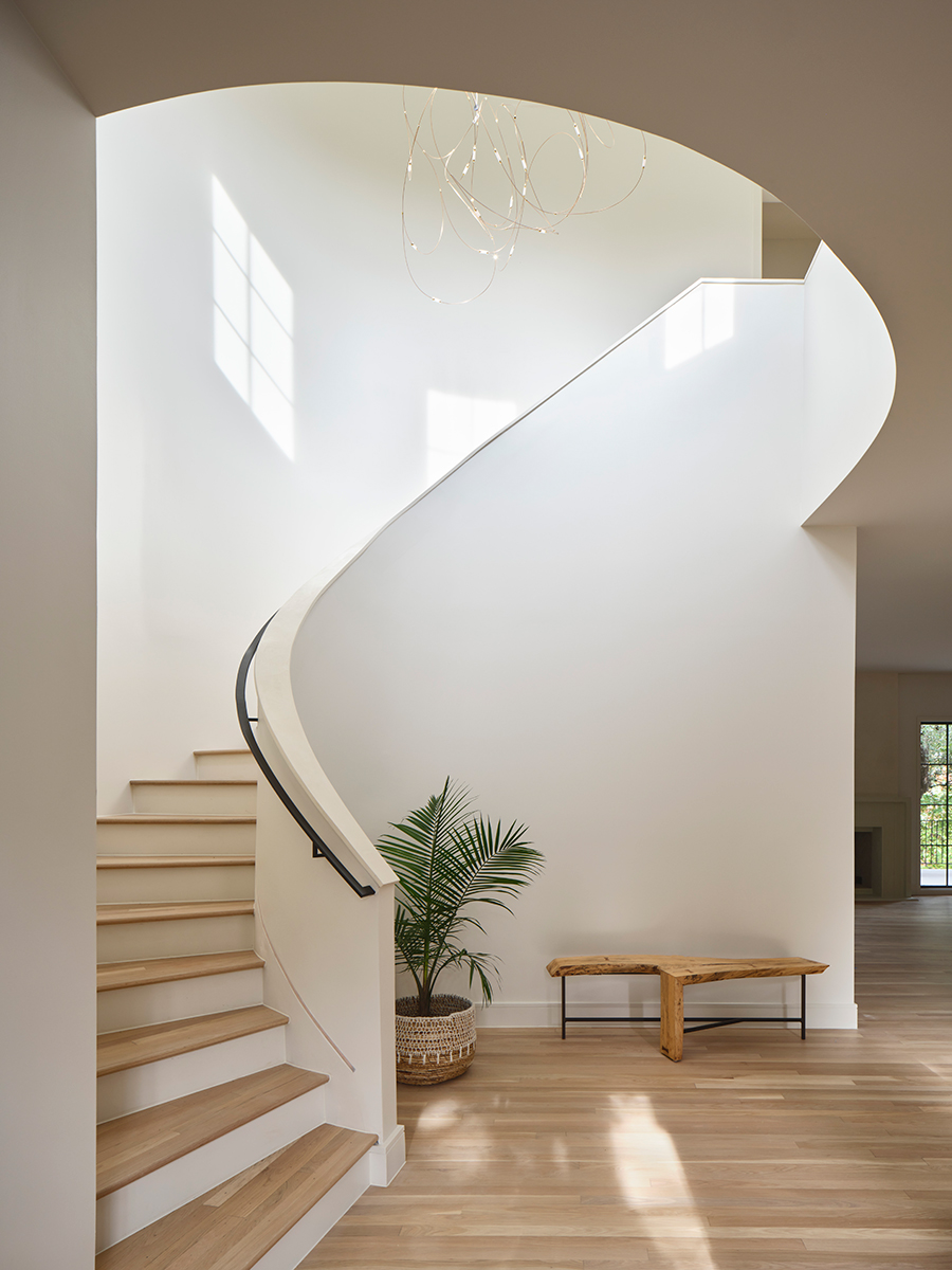 The curved staircase that serves as a grand entrance for the home and allows natural light to flow into the renovated living space