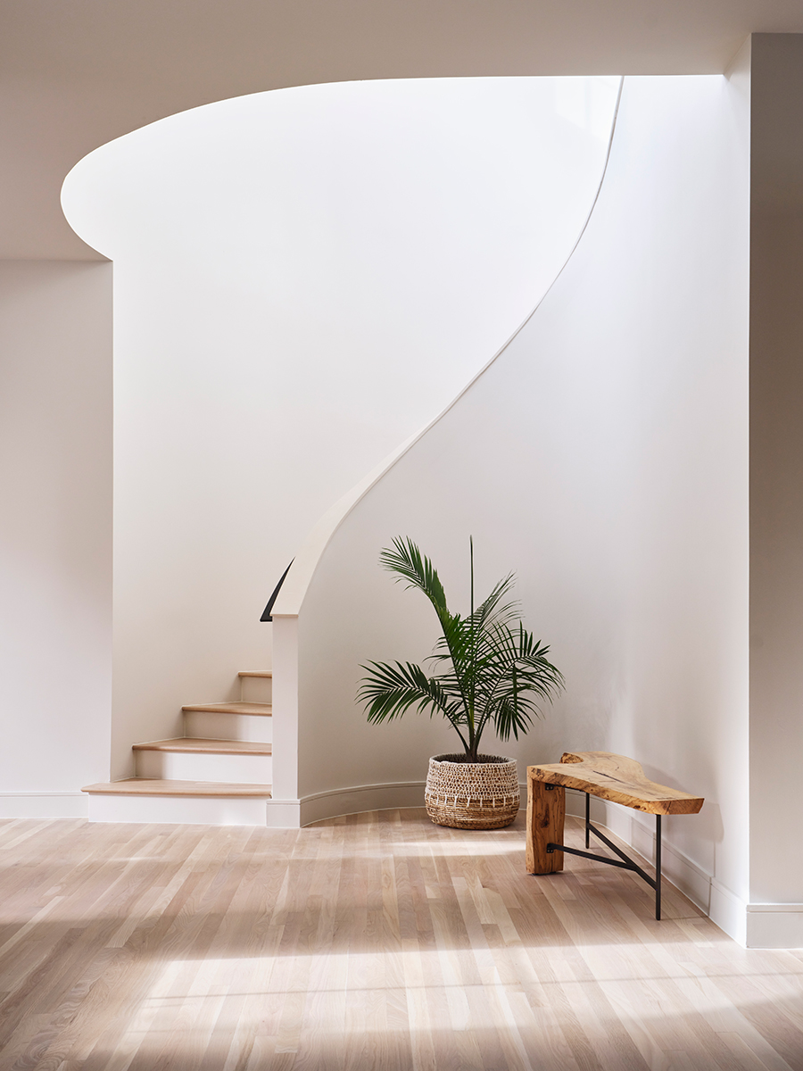 The curved white walls of a new staircase in this renovated entryway.