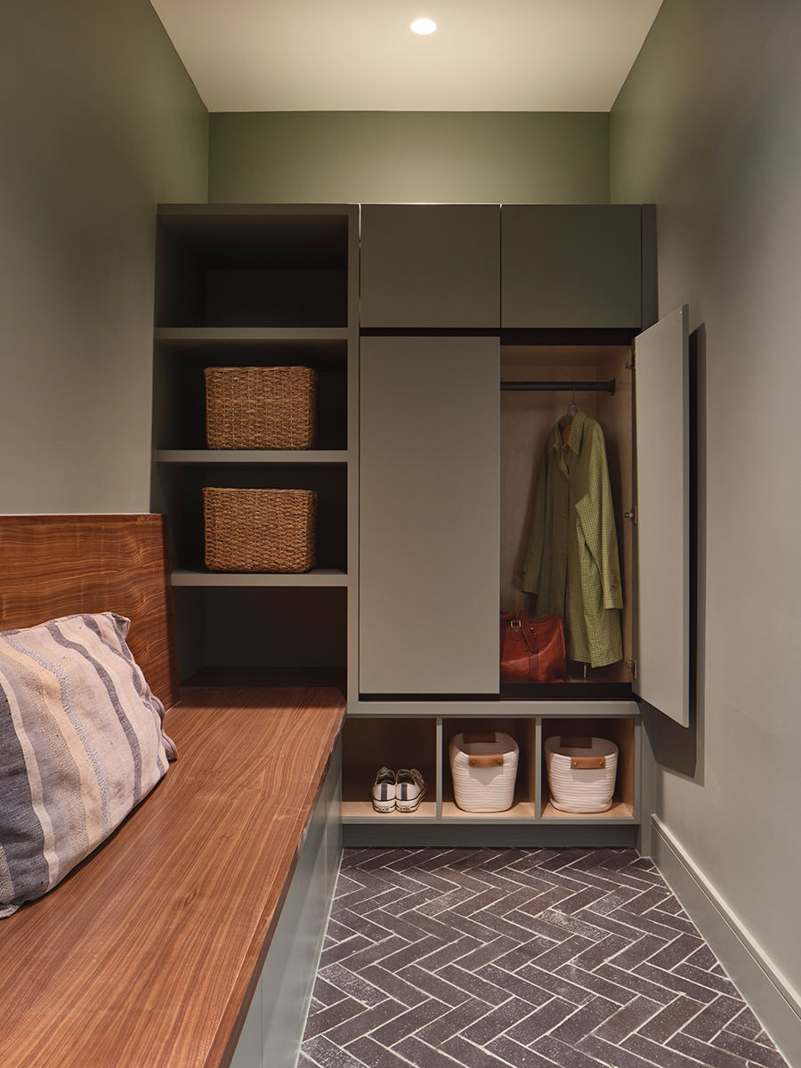 The new master closet in a renovated historic home with built-in wood bench and sage painted cabinets.