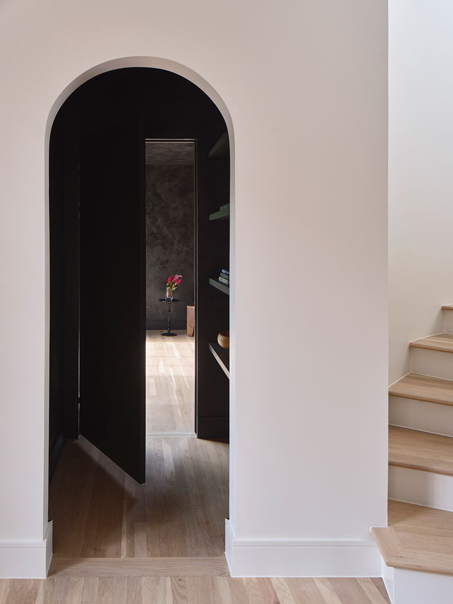 A bright arched hallway entry leads to a dark painted hallway in this home renovation.