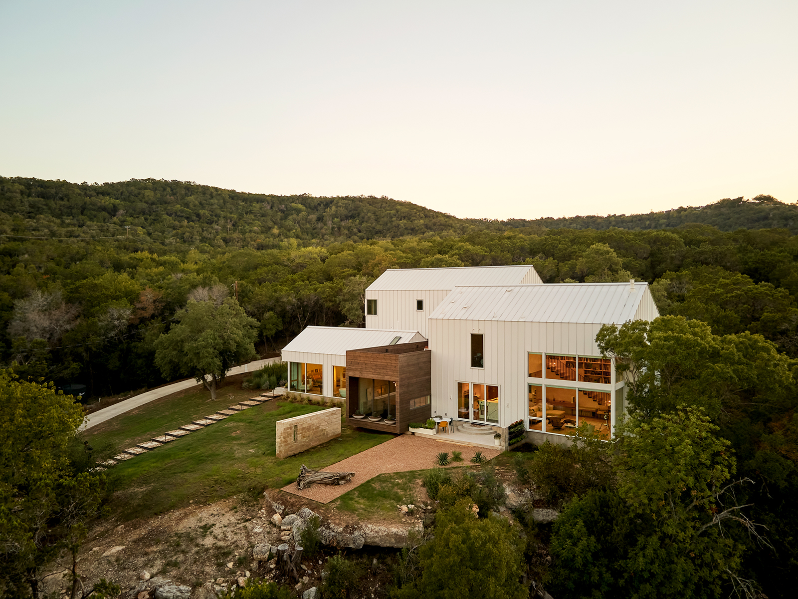 Modern new construction home exterior view in hill country landscape.