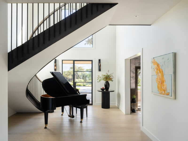 House Renovation & Addition in Austin, TX - Main Hall with curved staircase & piano under it.