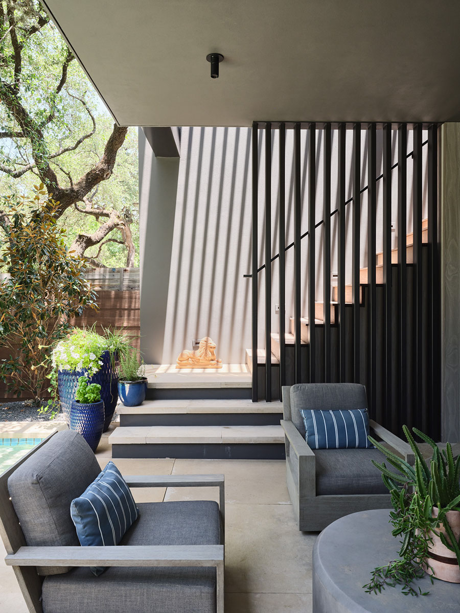 Outdoor seating area with gray lounge chairs and slatted staircase enclosure at the 5th Street House Addition in Austin, TX, built by Texas Construction Company and designed by FAB Architecture.