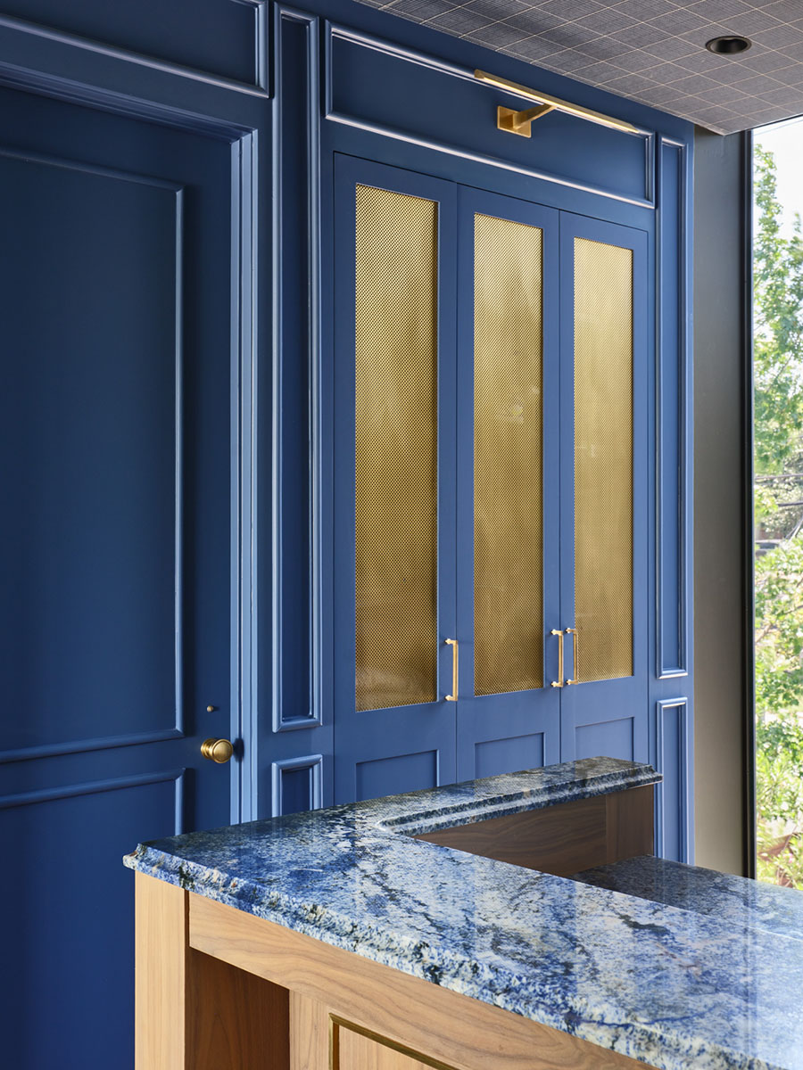 Detail view of custom blue paneled bar cabinetry with brass mesh doors and blue granite countertop at the 5th Street House Addition in Austin, TX.
