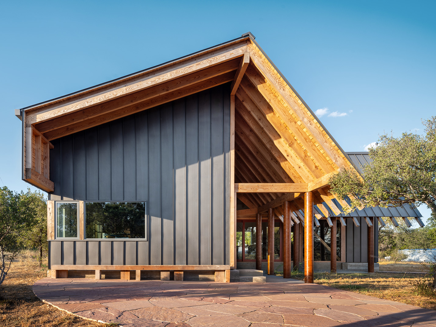 Exterior view of a custom home in Austin, TX featuring modern vertical siding, exposed wood framing, and unique architectural details by Ted Young Architecture and Texas Construction Company