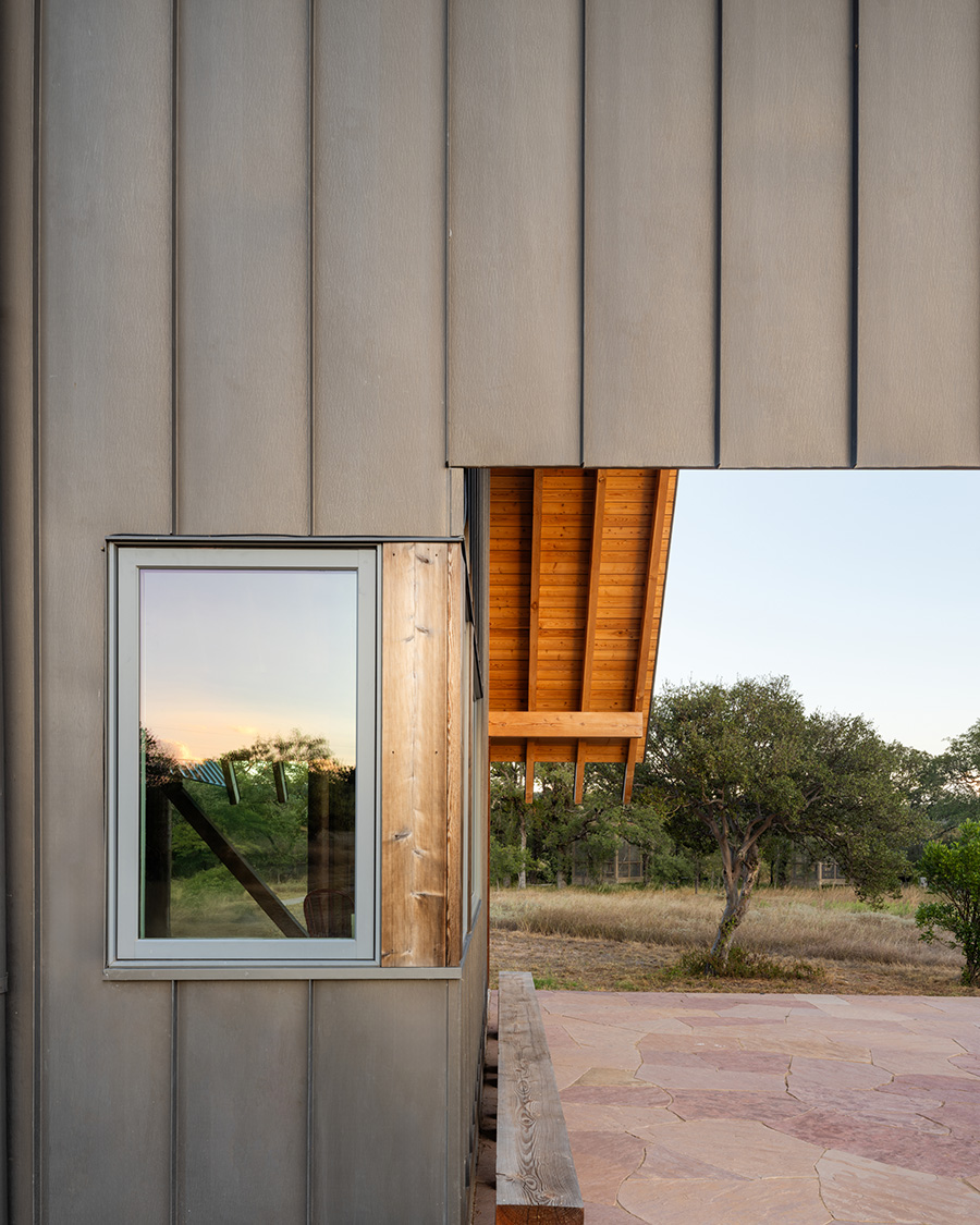 Close-up of window, vertical siding, and timber eaves on a custom home in Austin, Texas designed by Ted Young Architecture and built by Texas Construction Company