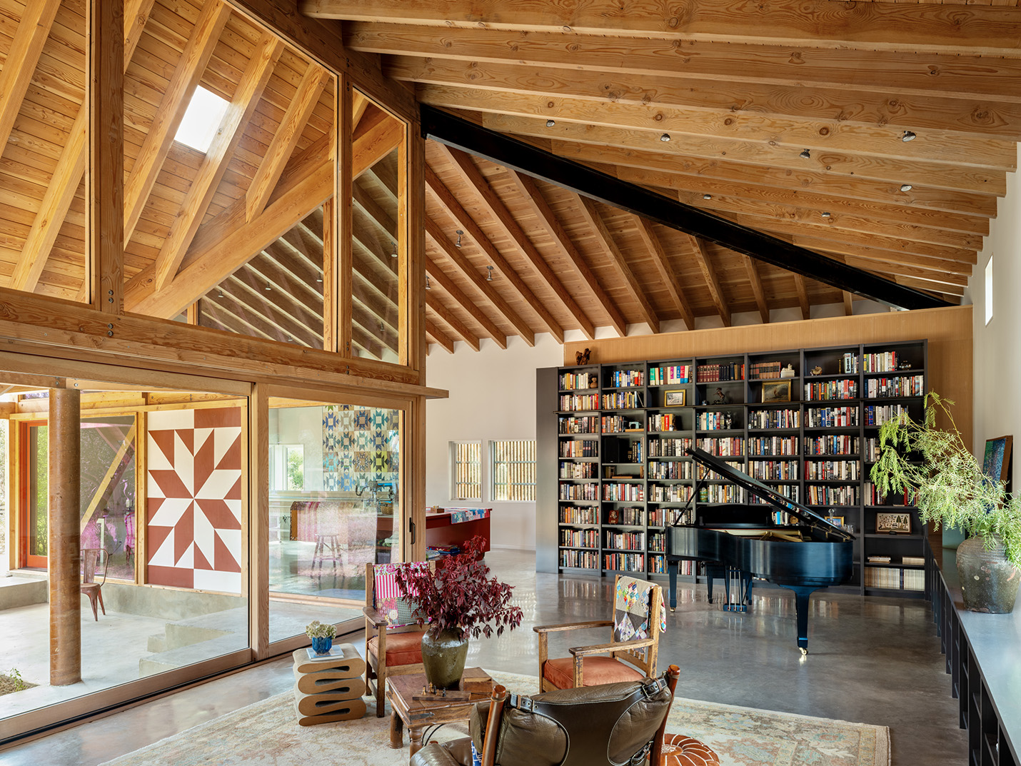 Library and music room with grand piano in a custom home in Austin, Texas featuring vaulted wood ceilings and modern architectural design by Ted Young Architecture and Design